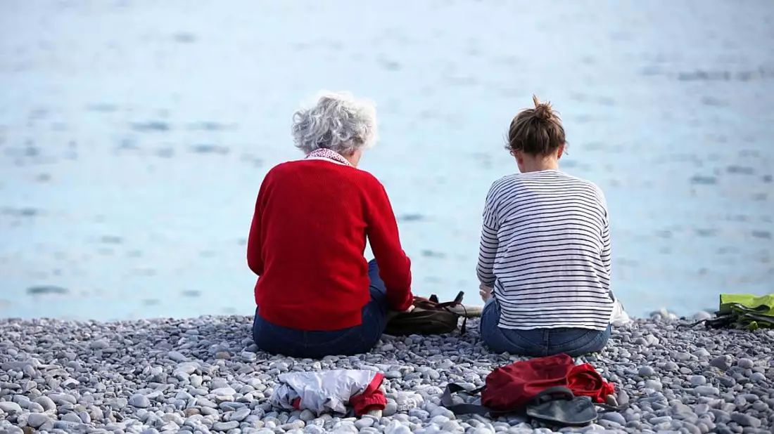Alte und junge Frau sitzen am Strand - Bild: über dts Nachrichtenagentur