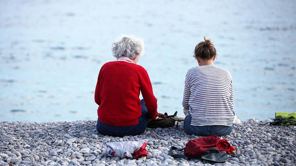 Alte und junge Frau sitzen am Strand - Foto: über dts Nachrichtenagentur