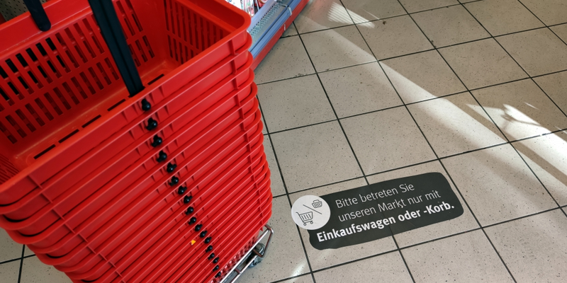 Einkaufskörbe mit Corona-Hinweis in Supermarkt - Foto: ?ber dts Nachrichtenagentur