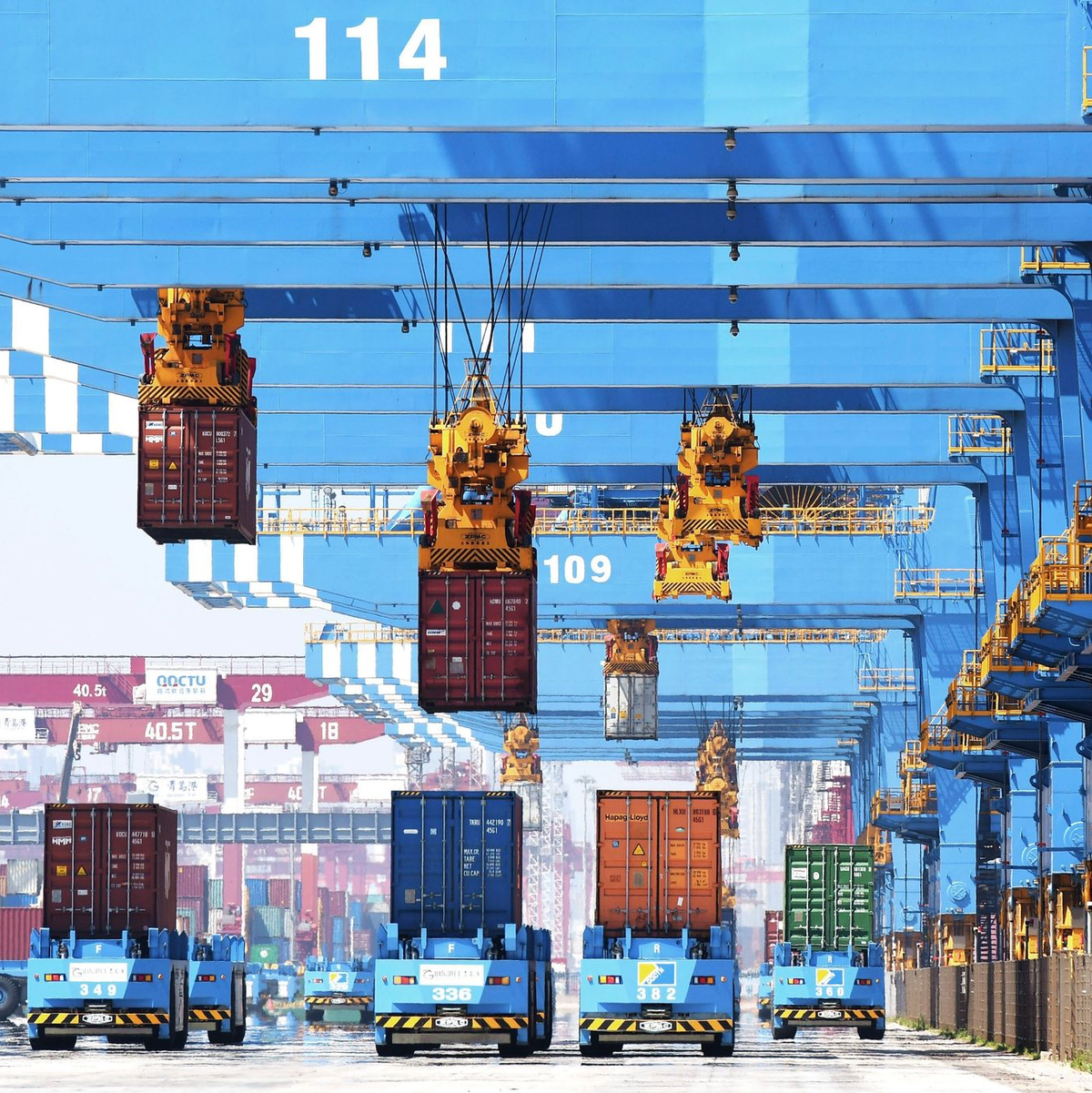 Portalkräne bewegen Container auf Transporter in einem Hafen in Qingdao in der ostchinesischen Provinz Shandong. - Foto: Uncredited/CHINATOPIX/dpa