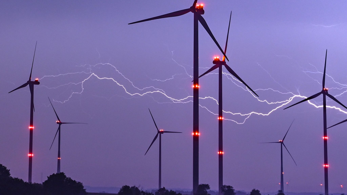 Ein Blitz leuchtet am Abendhimmel hinter einer Windenergieanlage im Osten Brandenburgs. - Foto: Patrick Pleul/dpa