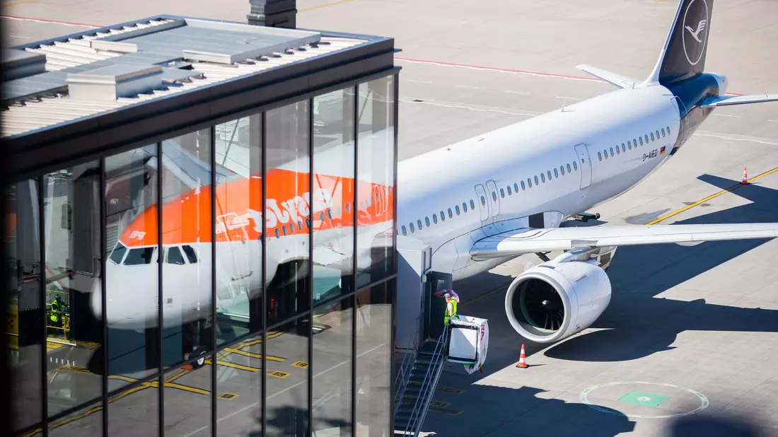 Passagiere stehen am Flughafen Berlin Brandenburg (BER) vor der Sicherheitskontrolle Schlange (Archivbild). - Bild: Christoph Soeder/dpa