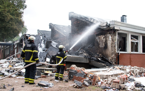 Polizisten stehen hinter einem Metallbehälter. Trümmerteile sollen bei dem Brand Hunderte Meter weit geflogen sein. - Foto: Daniel Bockwoldt/dpa Polizisten stehen hinter einem Metallbehälter. Trümmerteile sollen bei dem Brand Hunderte Meter weit geflogen sein. - Foto: Daniel Bockwoldt/dpa