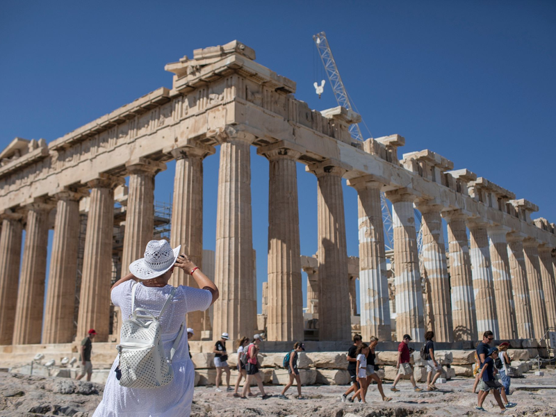 Touristen spazieren auf dem Lycabettus-Hügel, während der Himmel über Athen mit dem antiken Akropolis-Hügel im Hintergrund infolge von Saharastaub eingetrübt ist. - Foto: Petros Giannakouris/AP/dpa