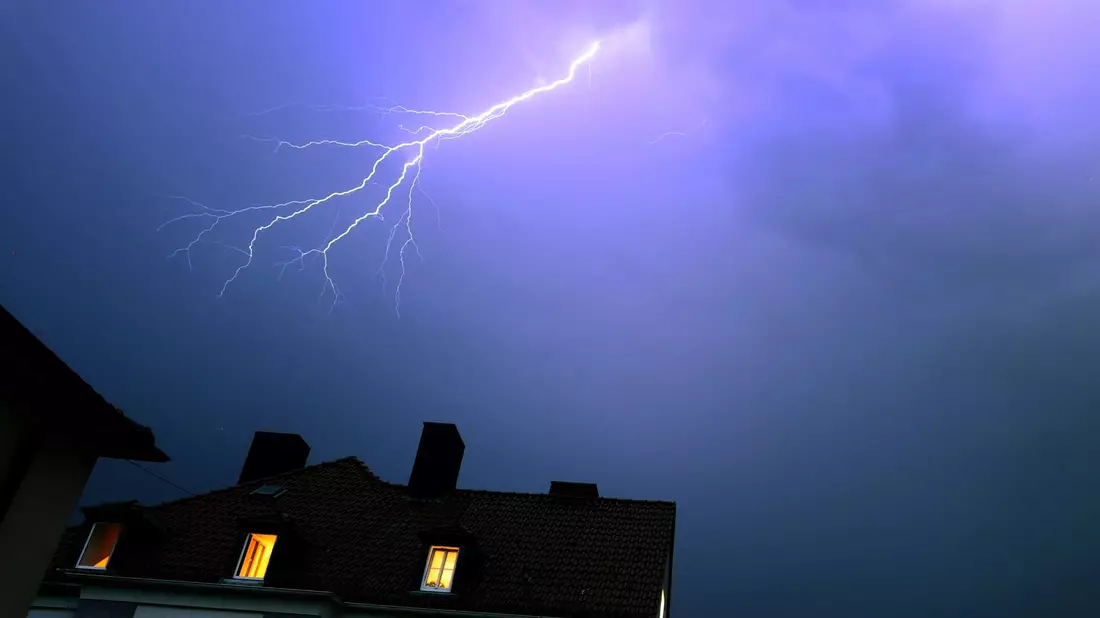 Ein Blitz erhellt den abendlichen Himmel über einem Kirchturm in Kaufbeuren. - Bild: Karl-Josef Hildenbrand/dpa