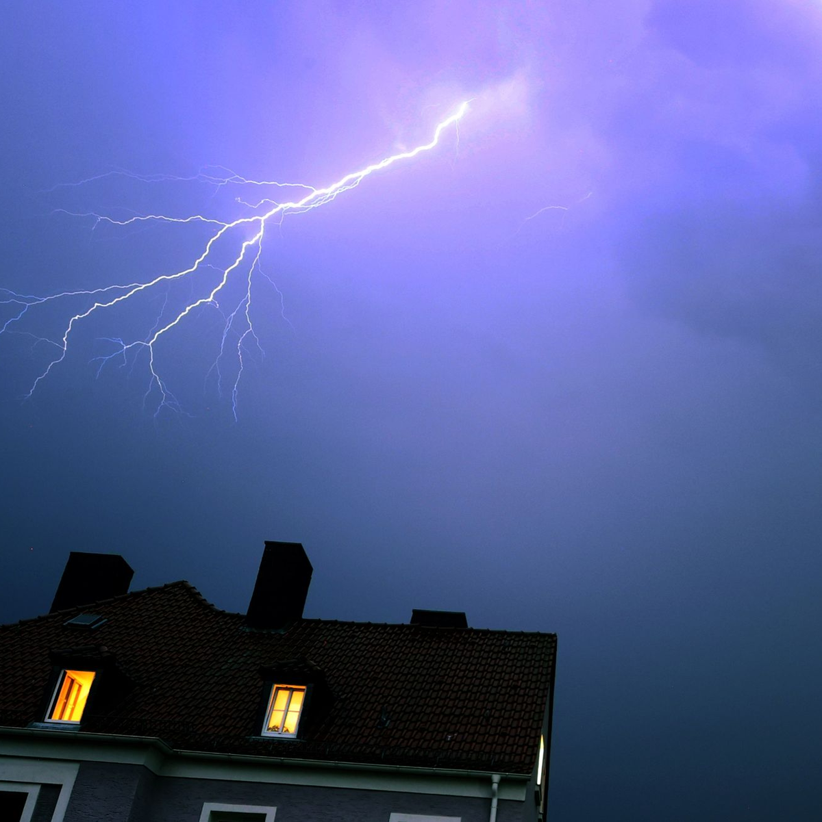 Ein Blitz erhellt den abendlichen Himmel über einem Kirchturm in Kaufbeuren. - Foto: Karl-Josef Hildenbrand/dpa