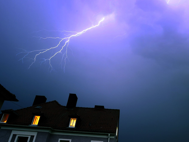 Ein Blitz erhellt den abendlichen Himmel über einem Kirchturm in Kaufbeuren. - Foto: Karl-Josef Hildenbrand/dpa
