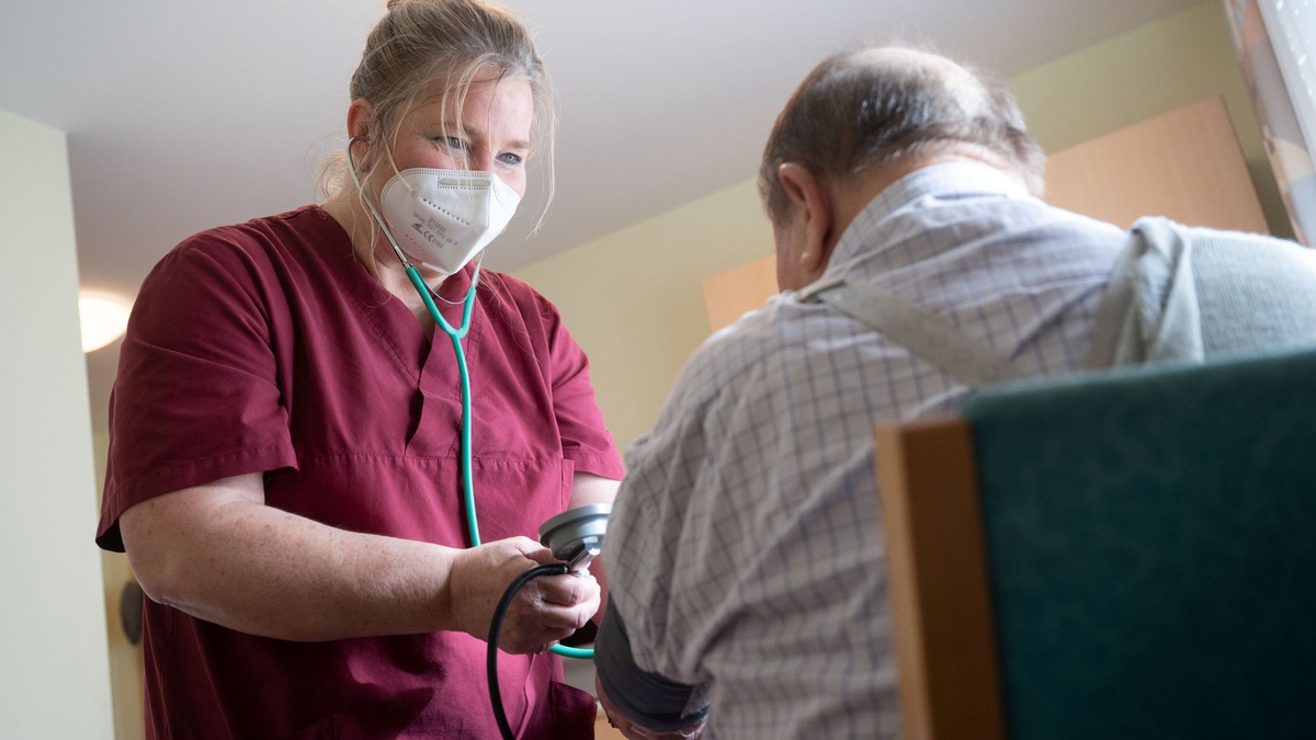 Eine Pflegekraft betreut in einem Seniorenhaus einen Bewohner. - Foto: Marijan Murat/dpa