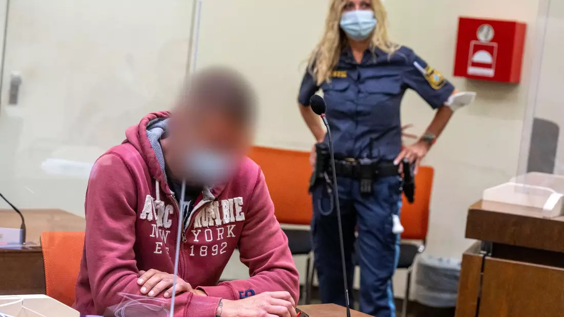 Der Angeklagte wird von der Polizei in den Gerichtssaal geführt. - Bild: Peter Kneffel/dpa