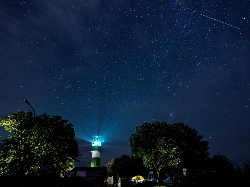 Eine Sternschnuppe zieht über dem Leuchtturm Bülk am Ufer der Ostsee ihre Bahn. - Foto: Axel Heimken/dpa