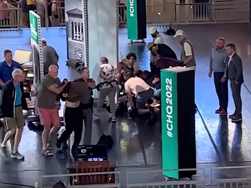 Menschen kümmern sich um den verletzten Rushdie, während ein Mann von der Bühne eskortiert wird. (Aufnahme kurz nach dem Angriff) - Foto: Uncredited/AP/dpa