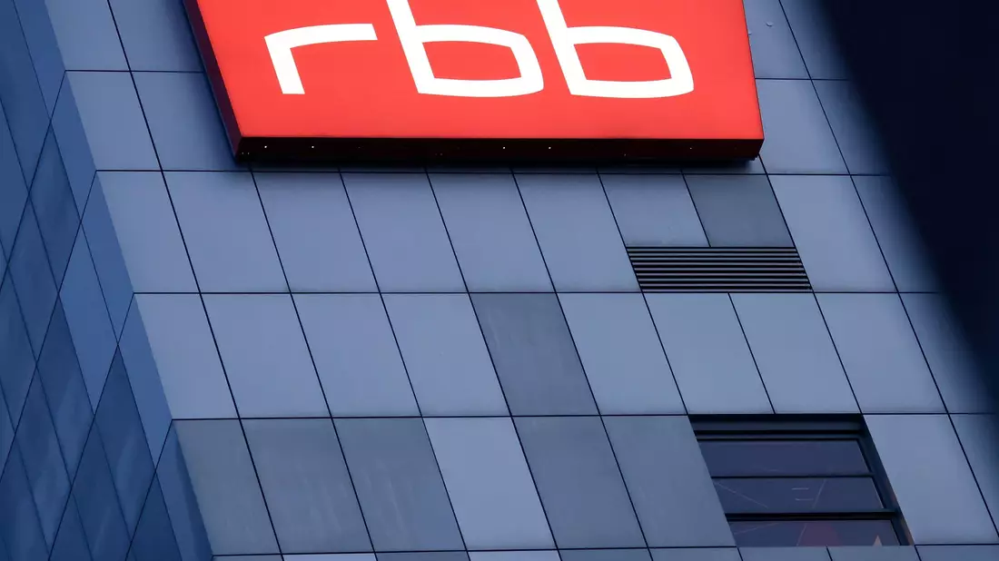 Das beleuchtete Logo des Senders Rundfunk Berlin-Brandenburg (RBB) an der Fassade am Sitz des Senders an der Masurenallee in Berlin. - Bild: Carsten Koall/dpa