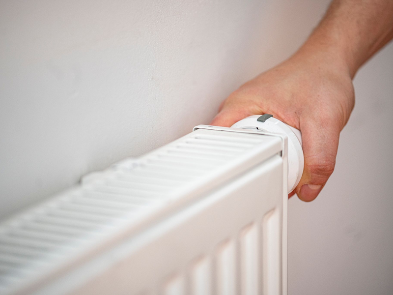 Eine Person benutzt einen alten Heizkörper in einer Berliner Altbauwohnung. - Foto: Fabian Sommer/dpa