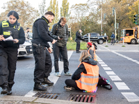 Ein Verkehrsteilnehmer zieht bei einer Blockade der Letzten Generation auf der Autobahn 100 eine Aktivistin von der Straße. Erneut hat die Klimaaktivistengruppe an zahlreichen Stellen in Berlin Straßen blockiert. - Foto: Paul Zinken/dpa