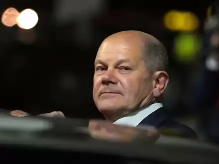 Bundeskanzler Olaf Scholz (l, SPD) kommt zum Start einer zweitägigen Reise auf dem militärischen Teil des Flughafens Berlin Brandenburg BER an und steigt aus einer Limousine. - Foto: Soeren Stache/dpa