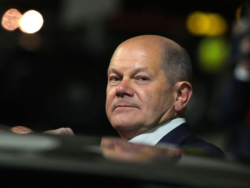 Bundeskanzler Olaf Scholz (l, SPD) kommt zum Start einer zweitägigen Reise auf dem militärischen Teil des Flughafens Berlin Brandenburg BER an und steigt aus einer Limousine. - Foto: Soeren Stache/dpa