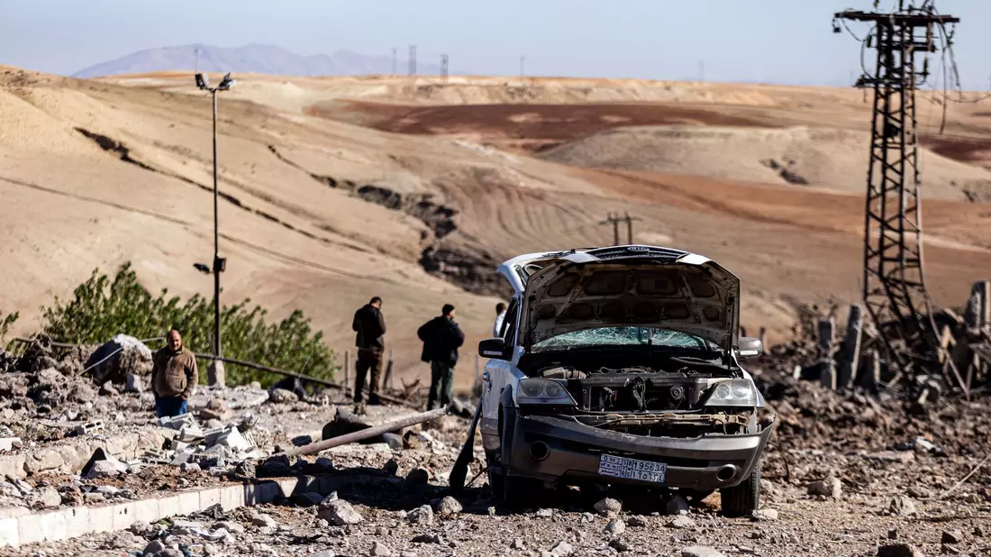 Zwei Männer begutachten Schäden in einem Gebiet um ein Elektrizitätswerk nach türkischen Luftangriffen. - Bild: Baderkhan Ahmad/AP/dpa