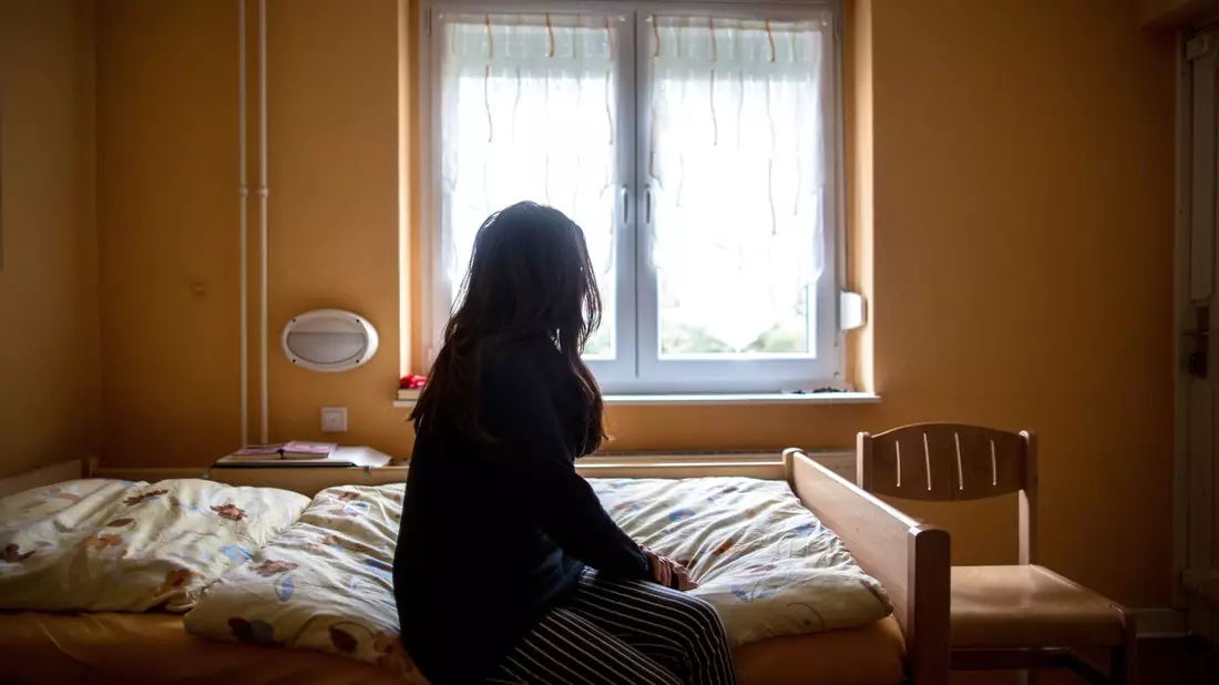 Eine Frau sitzt in einem Frauenhaus auf einem Bett. Tausende Frauen und Kinder haben auch 2022 zeitweilig Schutz in Schutzeinrichtungen gesucht. - Bild: Maja Hitij/dpa