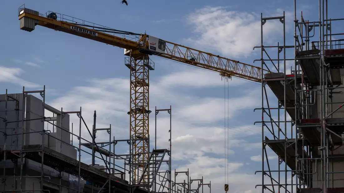 Ein Turmdrehkran ragt in den Himmel auf einer Baustelle: Das Baugewerbe ist vom Fachkräftemangel besonders stark betroffen. - Bild: Monika Skolimowska/dpa