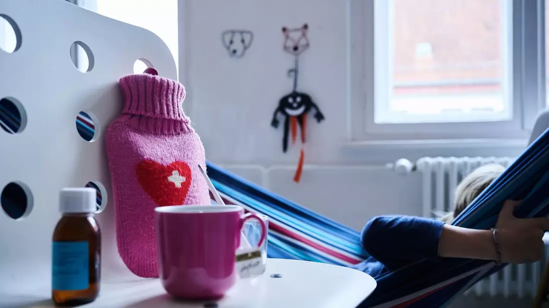 Fieberthermometer, Hustensaft, Wärmflasche und eine Tasse Tee: Die Wellen von Atemwegsinfektionen in Deutschland flachen langsam ab. - Bild: Annette Riedl/dpa