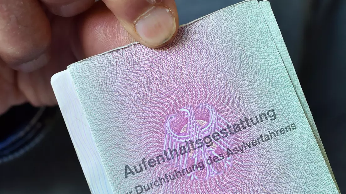 Ein aus Syrien geflüchteter Mann mit seiner Aufenthaltsgestattung. - Bild: Hendrik Schmidt/dpa