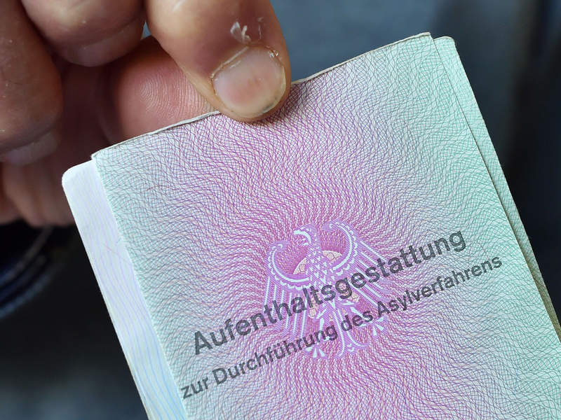 Ein aus Syrien geflüchteter Mann mit seiner Aufenthaltsgestattung. - Foto: Hendrik Schmidt/dpa