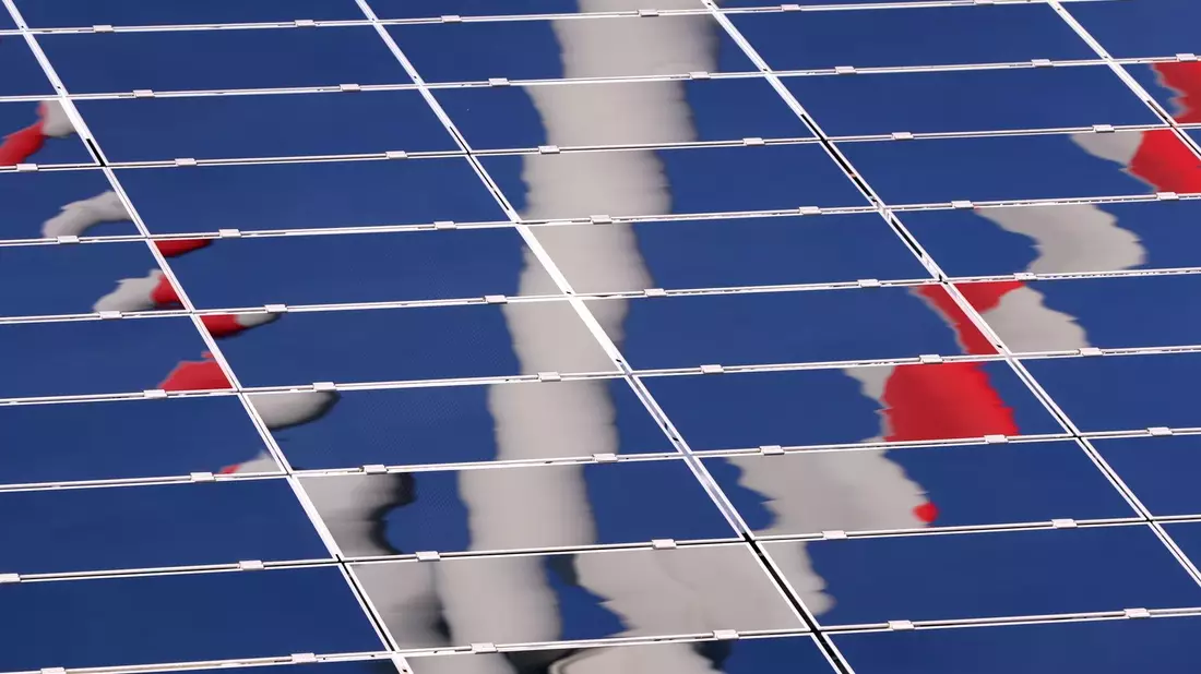 Ein Windrad spiegelt sich in einer Solar-Anlage. - Bild: Karl-Josef Hildenbrand/dpa