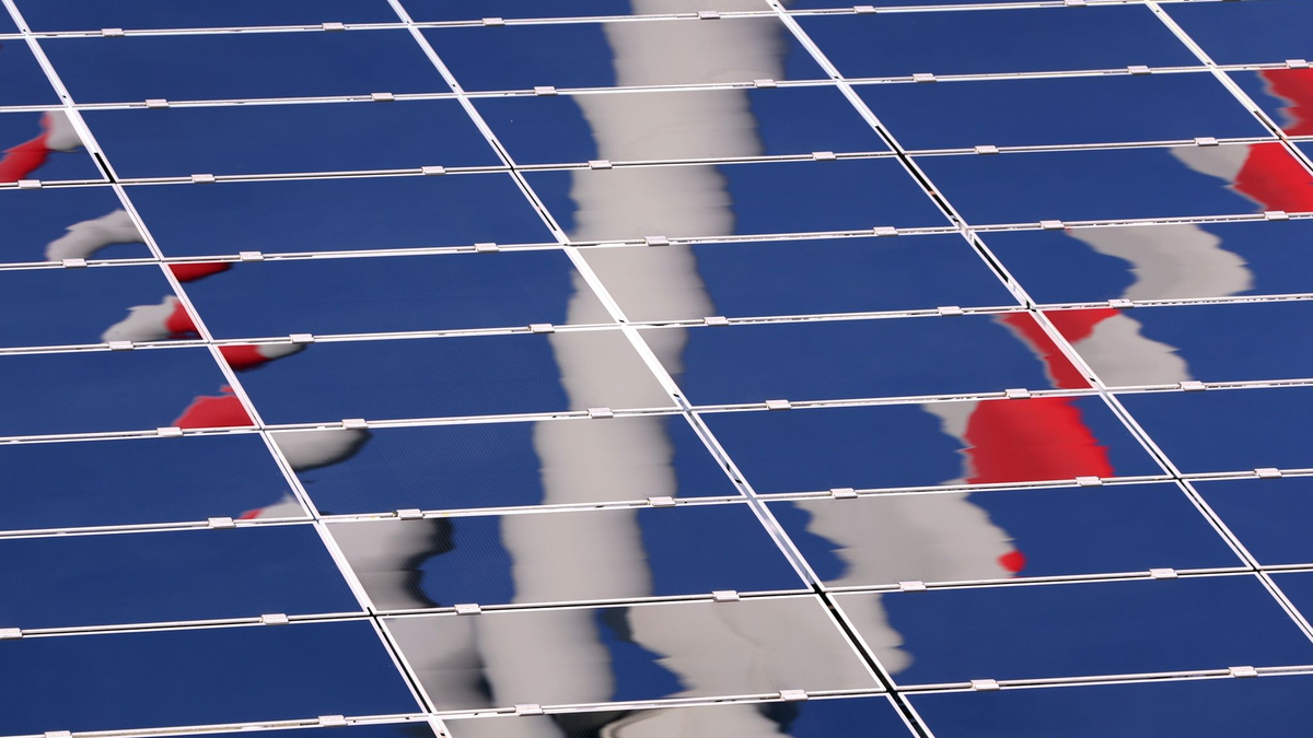 Ein Windrad spiegelt sich in einer Solar-Anlage. - Foto: Karl-Josef Hildenbrand/dpa