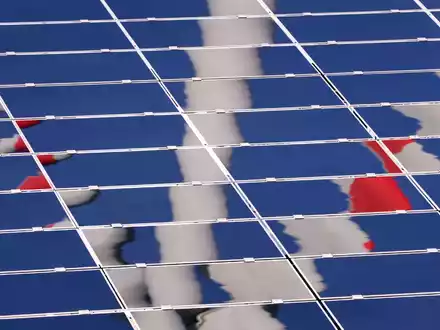 Ein Windrad spiegelt sich in einer Solar-Anlage. - Foto: Karl-Josef Hildenbrand/dpa