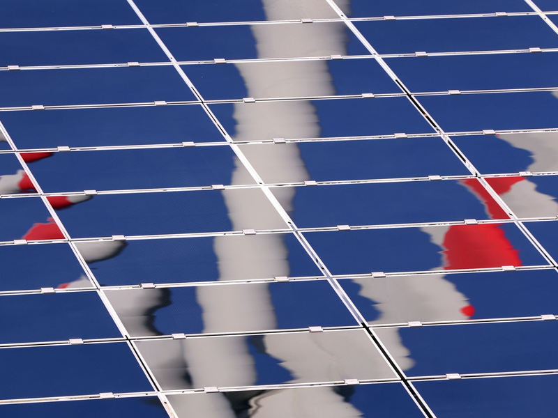 Ein Windrad spiegelt sich in einer Solar-Anlage. - Foto: Karl-Josef Hildenbrand/dpa