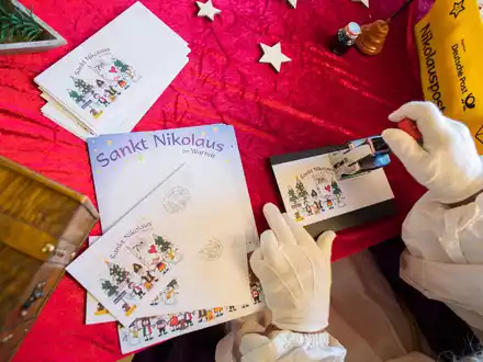 Der Nikolaus im Nikolauspostamt stempelt Briefe, die Kinder als Antwort auf ihre Briefe bekommen. - Foto: Oliver Dietze/dpa