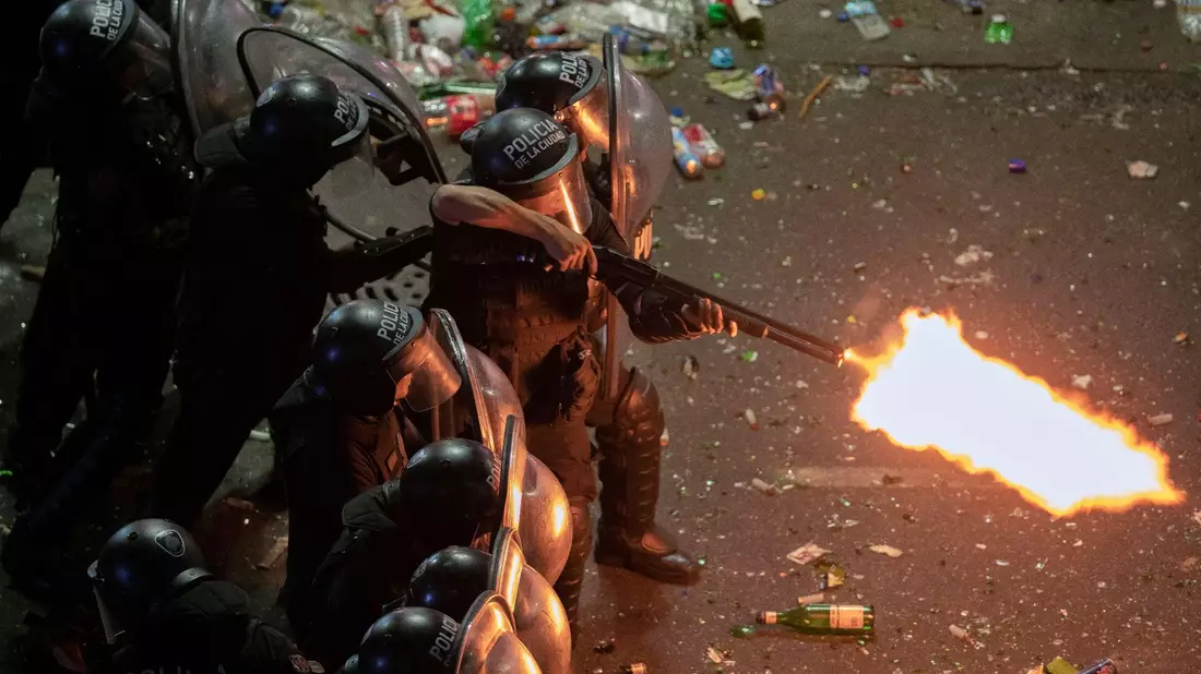 Ein Polizist der argentinischen Bereitschaftspolizei feuert eine Schrotflinte, nachdem eine Parade zur Feier der Weltmeister in Buenos Aires abrupt abgebrochen wurde. - Bild: Victor Caivano/AP/dpa