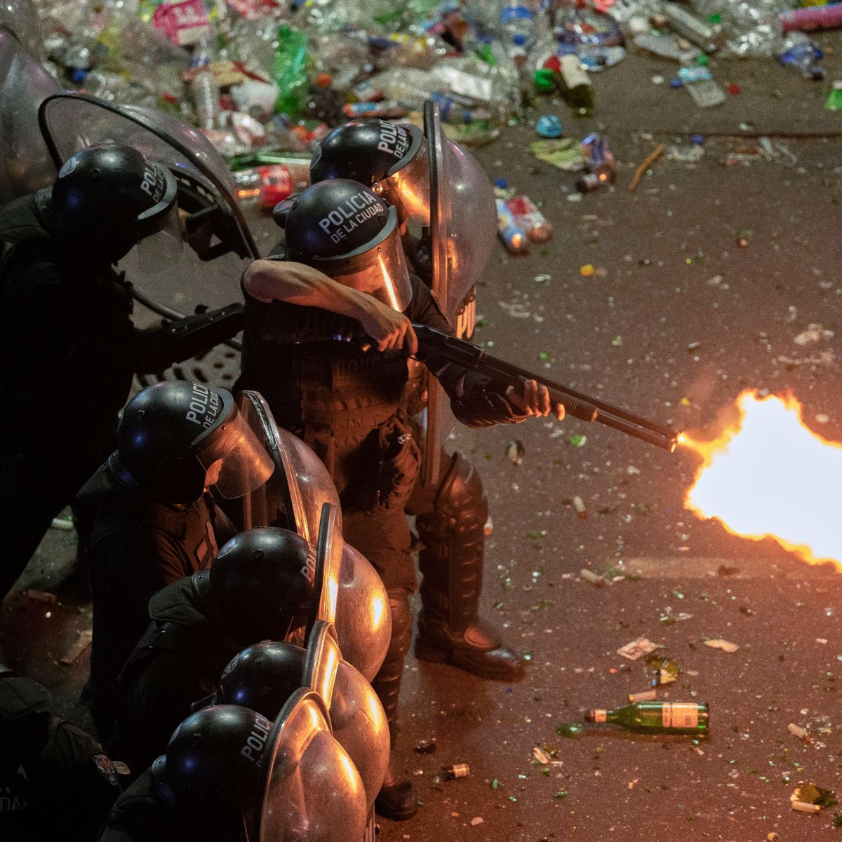 Ein Polizist der argentinischen Bereitschaftspolizei feuert eine Schrotflinte, nachdem eine Parade zur Feier der Weltmeister in Buenos Aires abrupt abgebrochen wurde. - Foto: Victor Caivano/AP/dpa