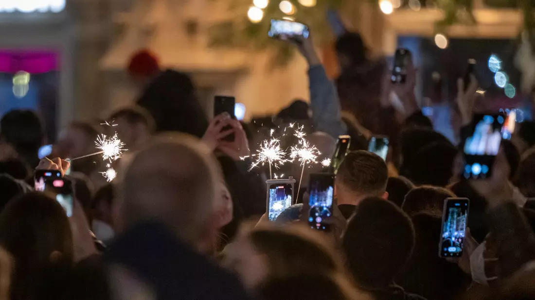 Menschen machen Fotos mit ihren Smartphones, während sie den Jahreswechsel feiern. - Bild: Peter Kneffel/dpa