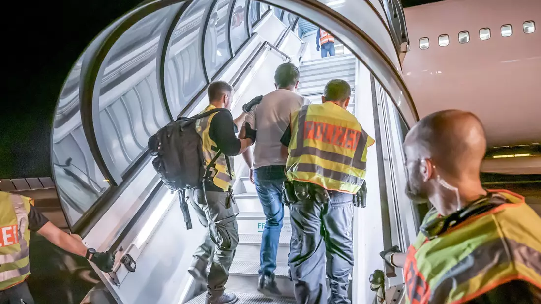 Abschiebung: Polizeibeamte begleiten einen Afghanen auf dem Flughafen Leipzig-Halle in ein Charterflugzeug. - Bild: Michael Kappeler/dpa