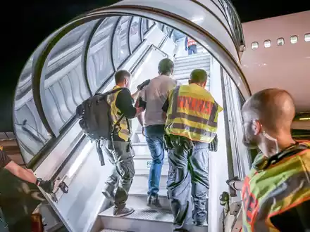 Abschiebung: Polizeibeamte begleiten einen Afghanen auf dem Flughafen Leipzig-Halle in ein Charterflugzeug. - Foto: Michael Kappeler/dpa