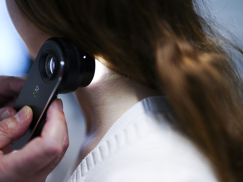 Ein Hautarzt untersucht bei einer Krebsvorsorgeuntersuchung eine Patientin mit einem Auflichtmikroskop. - Foto: Eva Manhart/APA/dpa