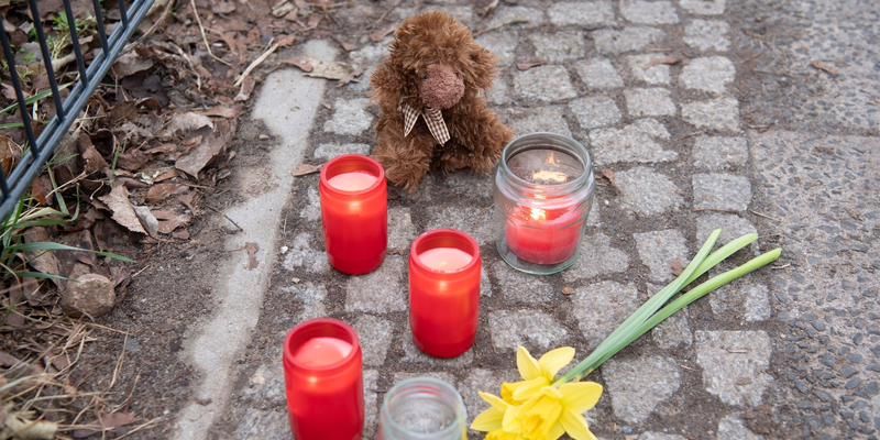 Kerzen und Blumen stehen unweit der Stelle, an der das verletzte Mädchen gefunden wurde. Trotz Reanimation verstarb es. - Foto: Paul Zinken/dpa