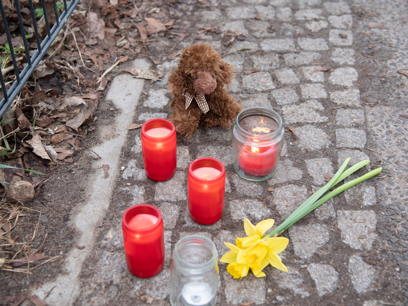 Kerzen und Blumen stehen unweit der Stelle, an der das verletzte Mädchen gefunden wurde. Trotz Reanimation verstarb es. - Foto: Paul Zinken/dpa