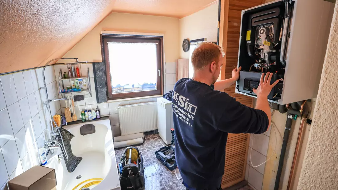 Ein Mitarbeiter einer Sanitär- und Heizungsbaufirma installiert eine moderne Gasbrennwerttherme in einem Einfamilienhaus. - Bild: Jan Woitas/dpa