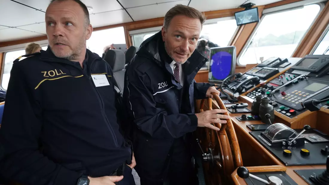 Finanzminister Christian Lindner (r)  steuert das Zollboot «Kehrwieder», links Zollkapitän Steffen Molter. - Bild: Marcus Brandt/dpa