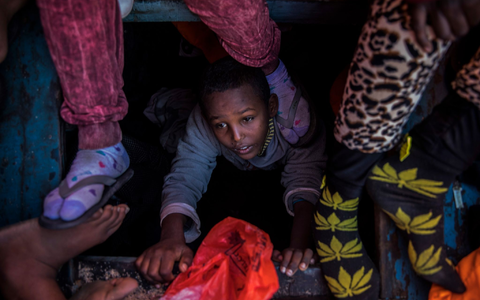 Ein Flüchtlingskind aus Eritrea versucht an der Küste zu Libyen, an Bord eines überfüllten Holzbootes hinaufzuklettern. - Foto: Santi Palacios/AP/dpa Ein Flüchtlingskind aus Eritrea versucht an der Küste zu Libyen, an Bord eines überfüllten Holzbootes hinaufzuklettern. - Foto: Santi Palacios/AP/dpa