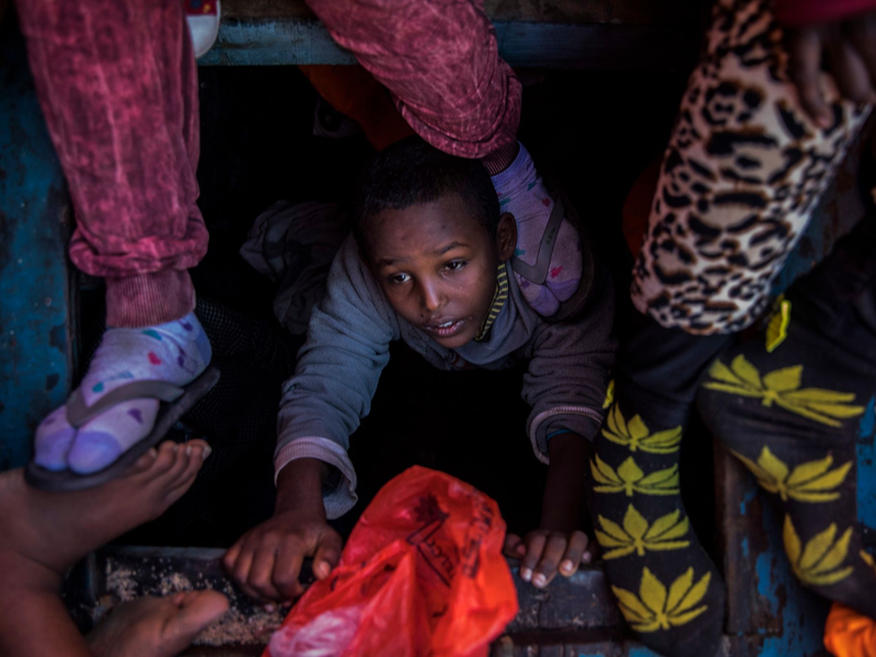 Ein Flüchtlingskind aus Eritrea versucht an der Küste zu Libyen, an Bord eines überfüllten Holzbootes hinaufzuklettern. - Foto: Santi Palacios/AP/dpa