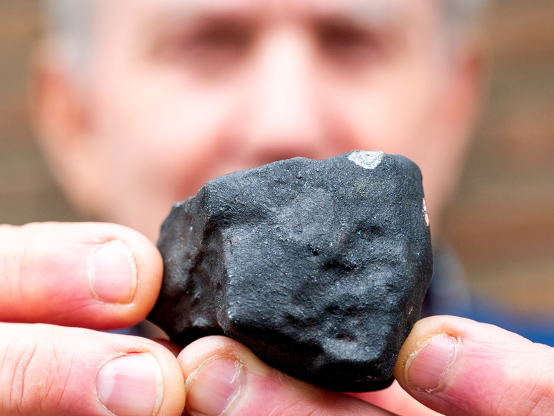 Hausbesitzer Wilfried Labusch mit einem kleinen Meteoriten, der niedergegangen ist. - Foto: Daniel Bockwoldt/dpa