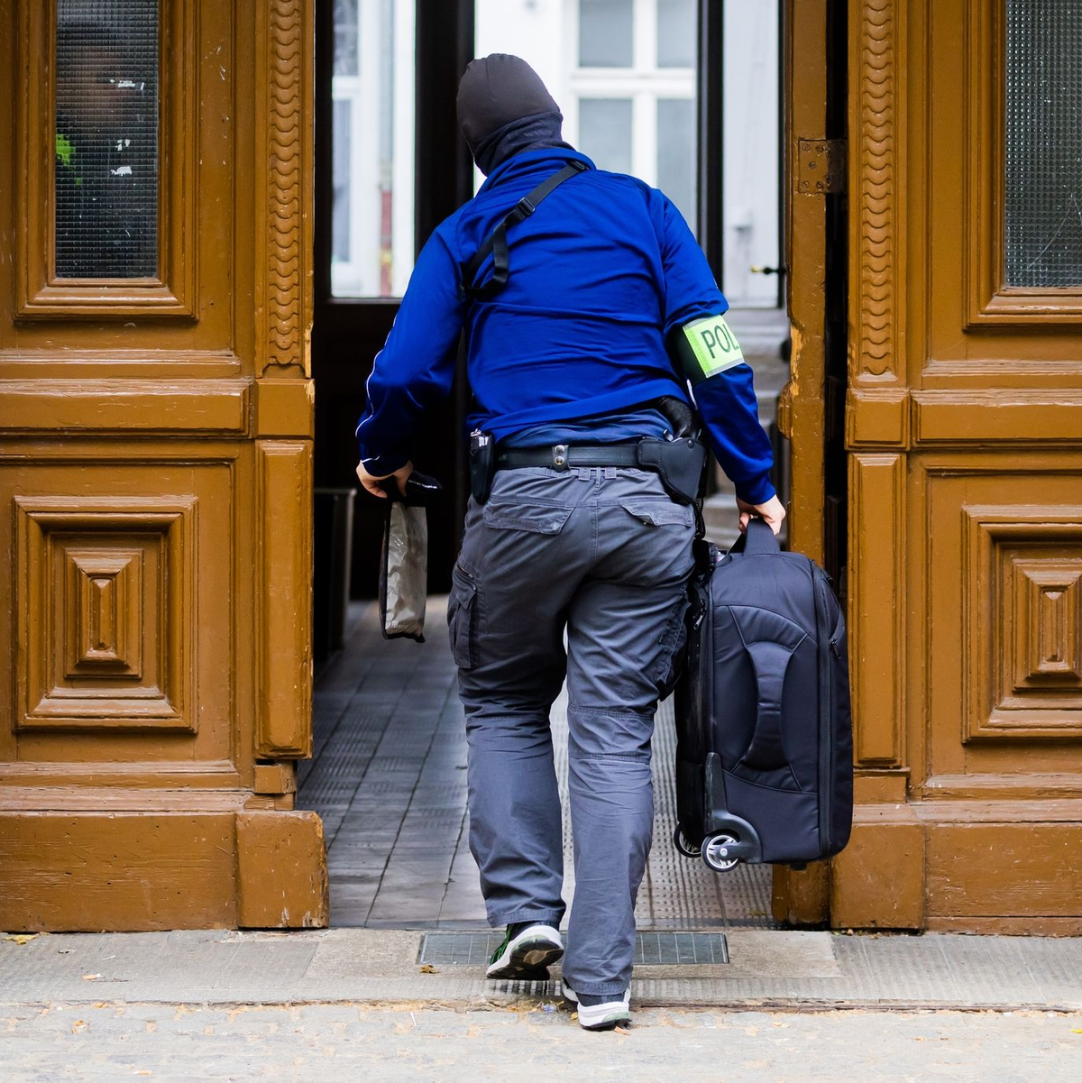 Ein Polizist während einer Hausdurchsuchung in Berlin-Kreuzberg - bundesweit waren mehrere Dutzend Beamte im Einsatz. - Foto: Christoph Soeder/dpa