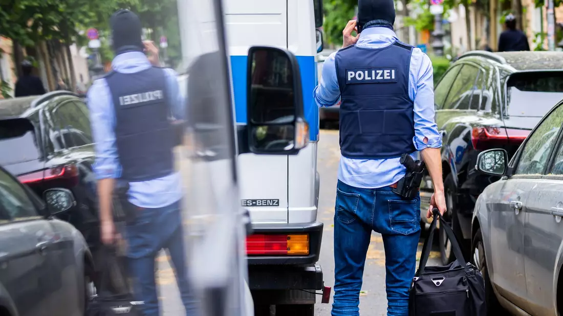 Polizisten tragen bei einer Hausdurchsuchung im Mai 2023 in Berlin-Kreuzberg einen Karton zu einem Fahrzeug. - Bild: Christoph Soeder/dpa