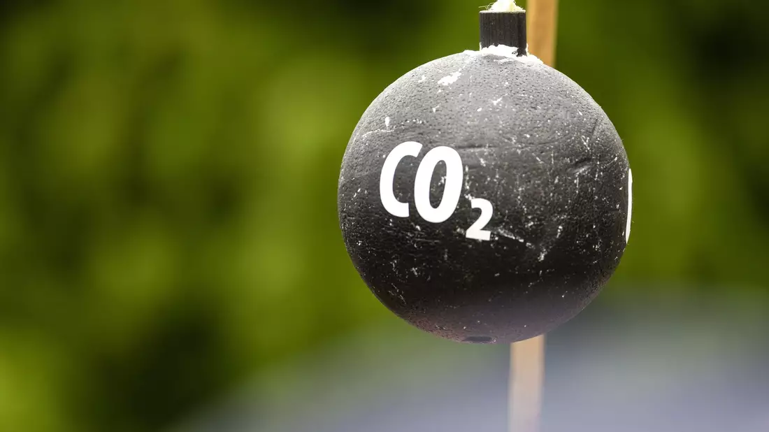 An einem Stab hängt vor Beginn einer Demonstration in Sachsen symbolisch eine «CO2-Bombe». - Bild: Frank Hammerschmidt/dpa