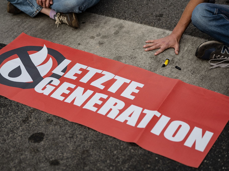 Ein Aktivist der Gruppe «Letzte Generation», der seine Hand selbst auf der Straße festgeklebt hat, blockiert eine Kreuzung in Göttingen. - Foto: Swen Pförtner/dpa