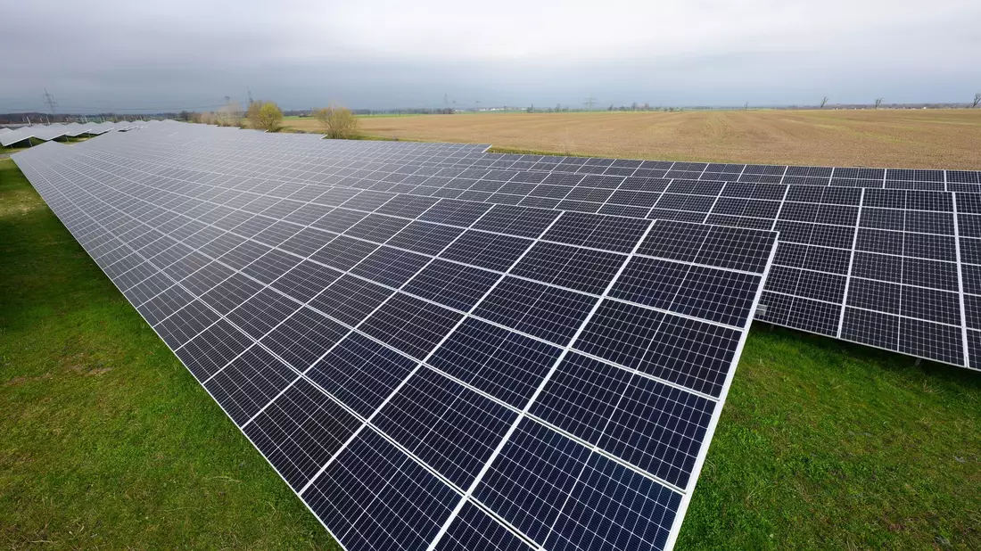 Solaranlagen sind für ein Photovoltaik-Speicher-Kraftwerk auf einer Wiese montiert. - Bild: Robert Michael/dpa