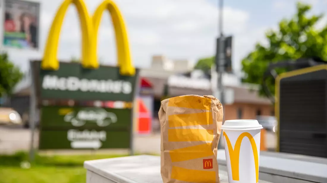 Eine McDonald's To-go-Tüte und ein dazugehöriger To-go-Becher stehen vor einer Tübinger McDonald's Filiale. - Bild: Christoph Schmidt/dpa